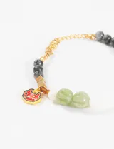 Pulsera elástica con cuentas de piedra natural en tonos gris, verde y blanco, con cadena dorada y charm esmaltado con forma de corazón.