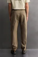 Pantalón técnico de corte regular fit en color marrón, confeccionado en tejido elástico y compacto. Cuenta con cintura ajustable con cordón interior, bolsillos frontales, bolsillo trasero con cierre oculto y bolsillo lateral con cierre en la pernera. El bajo es ajustable mediante botones a presión.