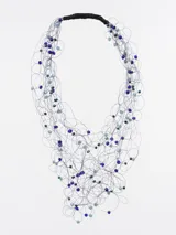 Collar de cuentas azules y celestes con hilos plateados y cierre de cordón negro.