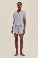 Conjunto de pijama de tela toalla color lavanda, compuesto por una camisa de manga corta con botones y un short con cintura elastizada y cordón ajustable.