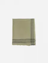 Pashmina rectangular color beige claro, con flecos en los bordes y diseño de líneas negras formando un patrón de cuadros en una esquina.