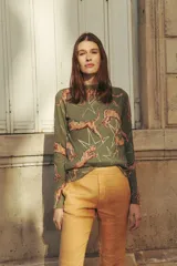 Sweater verde militar de cashmere con cuello redondo y mangas largas. Diseño estampado con leopardos color ladrillo y estrellas blancas.