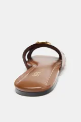 Sandalia plana color marrón con tiras cruzadas y detalle metálico dorado en la parte delantera.