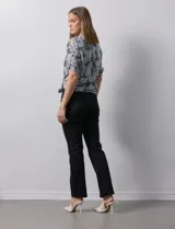 Blusa celeste con estampado blanco, de gasa, con cuello a la base y escote en V. Tiene abertura con botones, bolsillos delanteros y mangas 3/4 regulables con presilla y botón. El ruedo termina con un nudo.