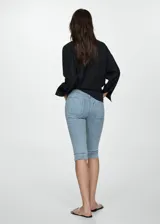 Jeans capri de corte skinny y tiro medio, confeccionados en tejido denim de algodón con elastano. Presentan costuras decorativas verticales en el frente, cierre de cremallera con botón, trabillas y bolsillos funcionales.