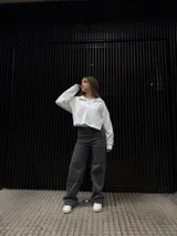 Pantalón de corte recto en color negro, confeccionado en tela elastizada de alta calidad. Presenta un diseño de tiro medio con detalle de tachas metálicas en la zona de los bolsillos delanteros.
