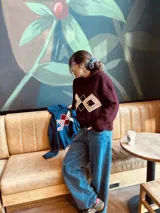 Canguro tejido en lana merino color azul con apliques geométricos en terciopelo bordados a mano.