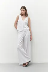 Pantalón blanco de lino, de corte ancho y con tajo lateral en el ruedo.