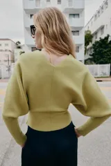Jersey de punto color verde lima, con cuello pico y manga larga de sisa ancha que se estrecha hacia la muñeca.