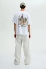 Remera blanca de punto de algodón, con cuello redondo y hombros caídos, corte holgado. Presenta un pequeño estampado en el pecho con el texto "MENTON FRANCE" en color oscuro.