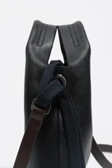 Bolso de hombro Bimba y Lola tamaño mini, de estructura blanda y color marrón oscuro, confeccionado en piel vacuna. Presenta asas de mano de piel y una correa extraíble, con detalles metálicos y logo de la marca en el frente.