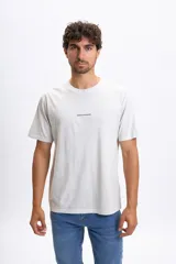 Remera de manga corta color gris claro con cuello redondo y un pequeño estampado minimalista en el pecho.