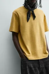 Camiseta de manga corta color crema, con cuello redondo y tejido texturizado con estructura.