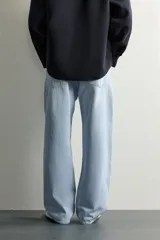 Jeans de denim de algodón en color azul con efecto desgastado, tiro medio y corte recto de ajuste holgado (loose fit). Cuenta con diseño clásico de cinco bolsillos y cierre frontal con cremallera y botón.