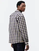 Camisa de manga larga con estampado a cuadros grandes en azul y blanco. Tiene cuello clásico, cierre con botones y un bolsillo en el pecho.