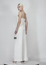 Blusa blanca estructurada en tweed con diseño halter y detalle metálico bordado en el cuello. Presenta una abertura frontal sutil y corte entallado en la cintura.