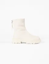 Botas de caña media en color blanco, confeccionadas en cuero vegano. Presentan una suela track con plataforma dentada y cierre metálico en la parte trasera.