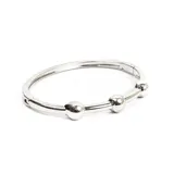 Pulsera rígida plateada con tres esferas decorativas.