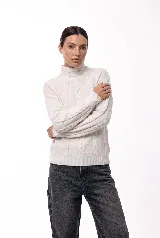 Polera de cuello alto confeccionada en tejido de punto suave, con diseño de trenzas verticales en el frente y mangas. Presenta puños y ruedo acanalados, ofreciendo un calce cómodo y versátil.