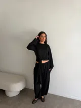 Conjunto negro de dos piezas que incluye una remera de manga larga con lazo ajustable para anudar en la cintura y un pantalón holgado de corte relajado con bolsillos.