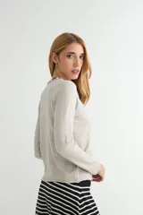 Sweater de punto negro con cuello redondo y detalle de borde ondulado, de manga larga y corte clásico.