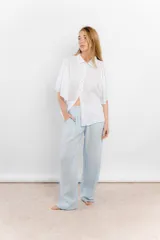 Camisa de lino color tostado, con cuello camisero y cierre frontal de botones. Se caracteriza por sus mangas cortas amplias y voluminosas que aportan un diseño fresco y liviano.