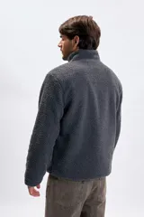 Buzo de sherpa en color gris oscuro, con cuello alto y cierre frontal parcial. Presenta un bolsillo frontal con cierre y diseño de manga larga.