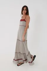 Vestido largo de algodón con estampado de rayas finas beige y negras, corte amplio con volados escalonados y detalles en color bordó en la pechera, breteles y ruedo.