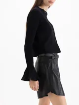 Cardigan negro de tejido de punto semi liviano, con calce al cuerpo, escote redondo y cierre frontal con botones. Mangas largas con puños godet acampanados que aportan volumen.