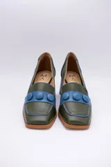 Zapato de cuero verde con aplique de cuero azul y botones forrados.