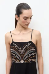 Maxi vestido largo de color negro, de corte recto y tirantes finos. Presenta un diseño bordado multicolor en la zona del pecho con motivos geométricos y florales.