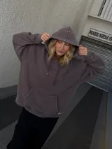 Buzo canguro marrón con capucha y cordones, de corte amplio y estilo urbano.