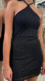 Vestido corto de encaje negro con escote halter y diseño ajustado al cuerpo.