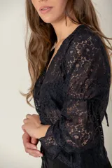 Blusa de encaje negro con escote en V, mangas tres cuartos y detalle de fruncido central con cordón ajustable.