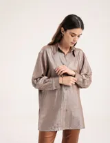 Camisa oversized con terminación metalizada color gris plomo. Tiene botones a tono en el delantero, largo por debajo de la cadera y tajos a los costados.