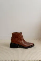 Bota corta de cuero marrón con panel trasero de gamuza en tono más oscuro, suela de goma negra y taco cuadrado bajo.
