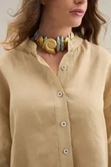 Camisa de lino de corte relajado, color beige, con cuello mao y cierre frontal de botones.