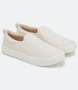 Championes slip-on color beige, sin cordones, con diseño capitoné en la parte frontal y suela blanca de goma.