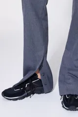 Pantalón de traje gris, de corte recto y tiro alto, con cierre de botón y cremallera.