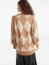 Sweater de punto con escote en V y diseño de rombos en tonos marrón y naranja. Presenta un corte holgado, mangas largas con puños acanalados y terminación de ruedo también acanalada.