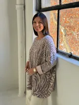Sweater de punto con diseño holgado y estampado animal print que combina motivos de cebra y serpiente en tonos neutros. Presenta cuello redondo y mangas largas con puños vueltos.