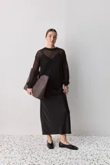 Falda midi color negro al bies, confeccionada en tela de textura suave y caída fluida, de diseño minimalista y silueta recta.