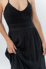 Vestido largo negro con top tejido en crochet y falda de gasa liviana con caída natural. Escote halter con breteles que atan al cuello y detalle de puntilla en la unión del busto.