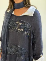 Sweater de punto azul con diseño holgado, que incorpora paneles de encaje floral en el frente y los laterales. Presenta un estilo superpuesto con cuello redondo y mangas largas con puños vueltos.