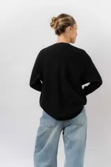 Buzo tejido de punto en color beige, con cuello redondo, mangas largas y silueta relajada con dobladillo irregular, siendo más largo en la parte trasera.