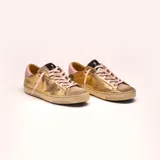 Zapatillas urbanas de cuero vacuno color dorado con detalles en rosa y taupe. Presentan cordones rosas, plantilla de 19 mm y suela de caucho con banda cosida.