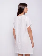 Vestido corto de corte holgado, color celeste, con cuello redondo fruncido y mangas cortas. Está confeccionado en una tela con textura diferenciada que le aporta relieve.