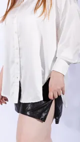 Camisa blanca de satén, corte holgado, con cuello clásico y cierre frontal con botones.