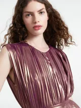 Mono largo sin mangas de corte holgado, confeccionado en tejido plisado con acabado metalizado. Presenta cuello redondo con detalle de abertura y cierre de botón en la parte posterior.