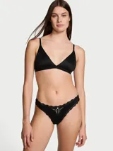 Panty tipo colaless de microfibra negra con detalles de encaje en los bordes y un aplique de encaje transparente en el centro delantero con un detalle de roseta decorativa.